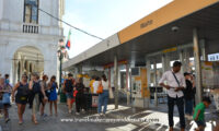 People outside during the day at a ferry ticket booth in Venice, Italy.