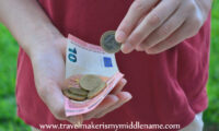 Person holding a 10 Euro note and some coins.