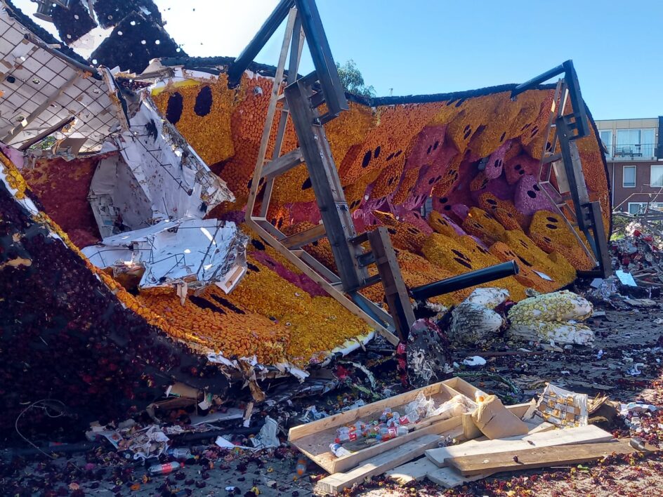 A partially dismantled float in the street with structures showing.