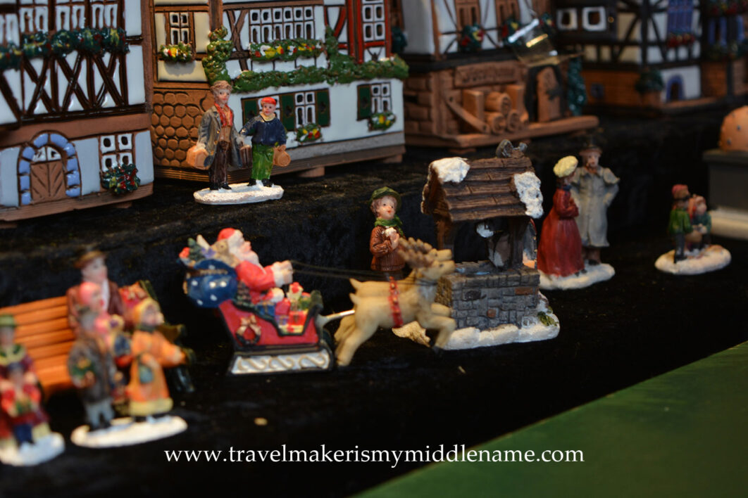 Handmade clay figurines: Santa in a sleigh being drawn by a pair of reindeers, some village people, and a wishing well
