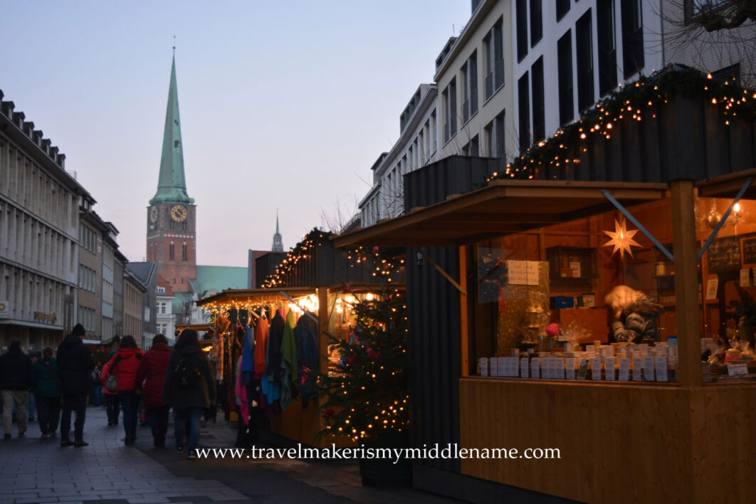 Christmas market stalls selling scarves in Lübeck with the Marien church in the far background