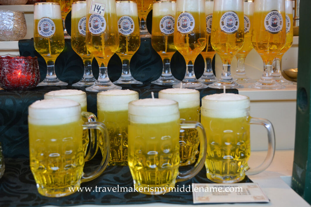 Flensburger beer shaped yellow candles in wine glasses in the back and beer glasses in the front