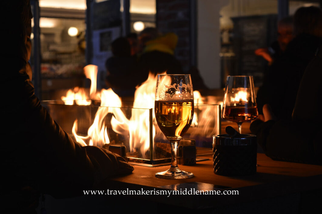 Yellow flames of a warm outdoor fire behind glass on a table where people are enjoying drinks in Lübeck in winter