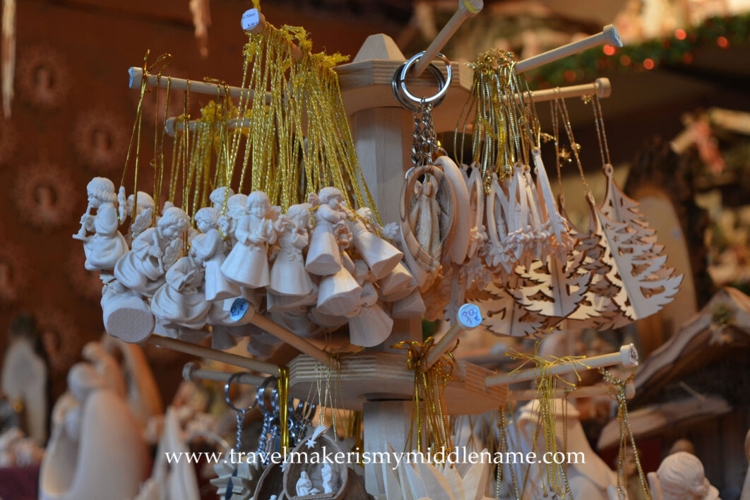 Wooden tree ornaments of angels hanging from a display rack.