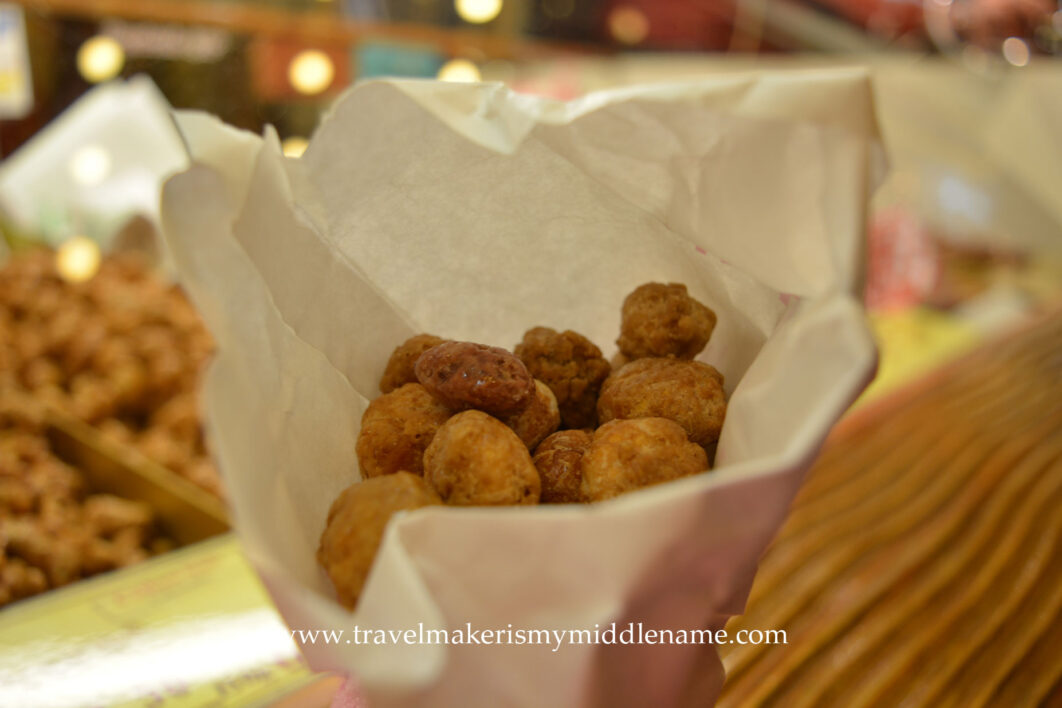 A paper cone of roasted almonds covered in a crispy sugar shell
