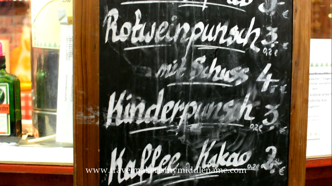 A menu at a Christmas market in Germany showing drinks: red wine punch, Kinderpunsch, and coffee or hot chocolate.