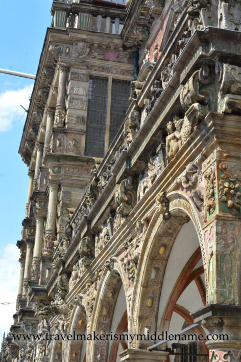 The stone arches of the Bremer Rathaus against a blue sky and clouds.