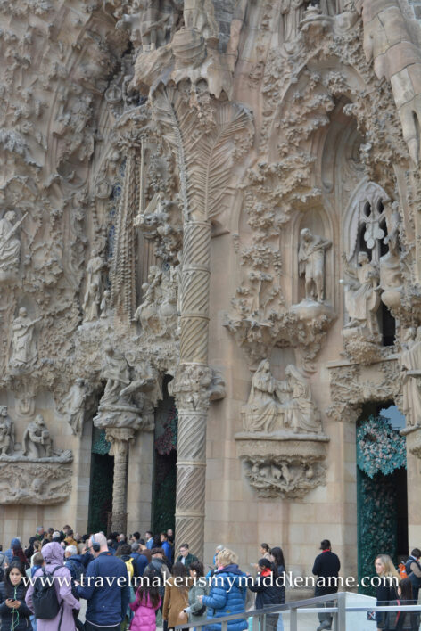 Visitors outside the facade of La Sagrada Familia church in Barcelona, Spain. Detail of a screw-thread style column and many of the sculptures on the facade.