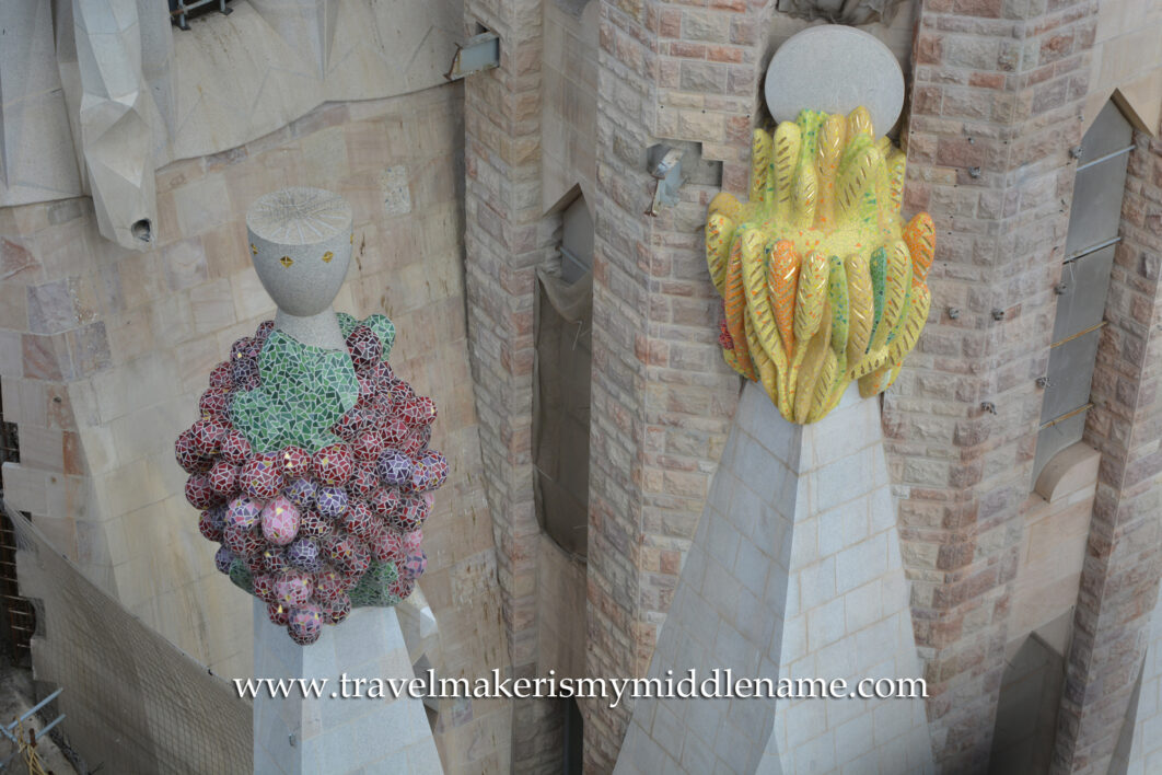 Sculptures of a cluster of purple grapes and yellow fruit seen from the Passion tower of La Sagrada Familia cathedral in Barcelona, Spain.