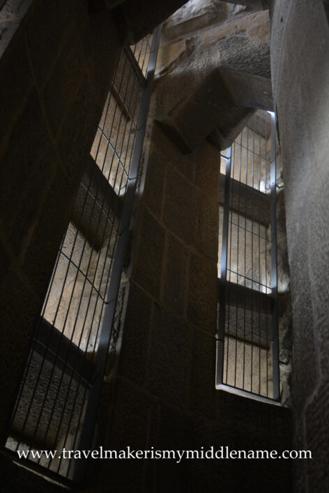 Metal grates cover openings cut into the curved stone walls of the Passion tower in La Sagrada Familia cathedral in Barcelona, Spain as seen from the tower.