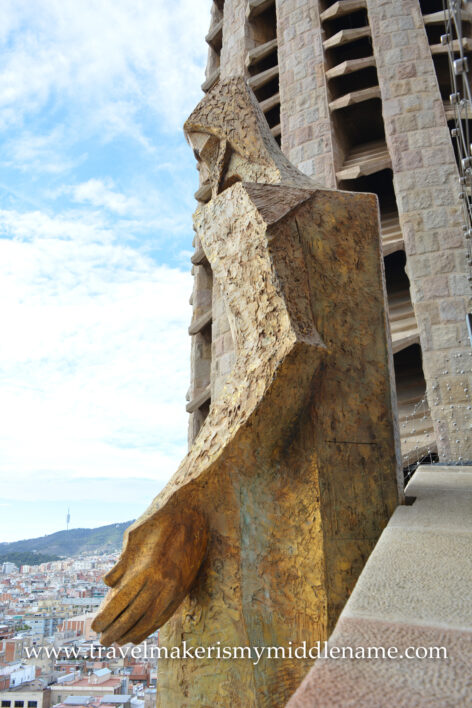 A large, golden cuboid statue of Jesus hanging over the city is attached to the bridge at the top of the Passion tower of La Sagrada Familia cathedral in Barcelona, Spain.