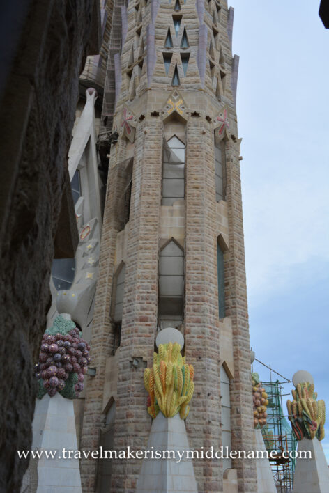 A view of one of the towers in La Sagrada Familia church in Barcelona, Spain, as seen from a small window in the Passion Tower. The bright yellow sculpture represents fruit, a common motif in the Passion tower.