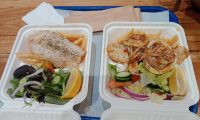 Two packs of grilled fish fillets with salad, lemon, and hot potato chips